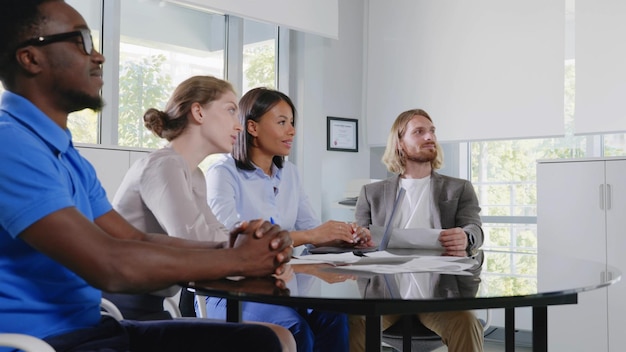 A group of diverse employees gathered in a conference room, discussing healthcare benefits with a human resources representative. The atmosphere is collaborative and informative.