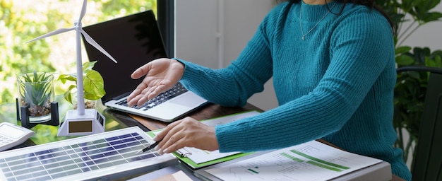 A person using a laptop to research and calculate tax credits for renewable energy investments, with a calculator and documents on the desk. The image represents the process of understanding and applying for tax credits.