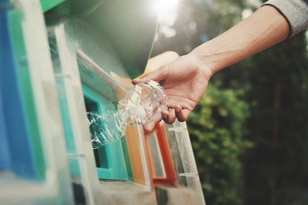 A close-up shot of hands sorting recyclable materials, with separate bins for paper, plastic, and glass clearly labeled. The focus is on effective waste management and recycling practices.