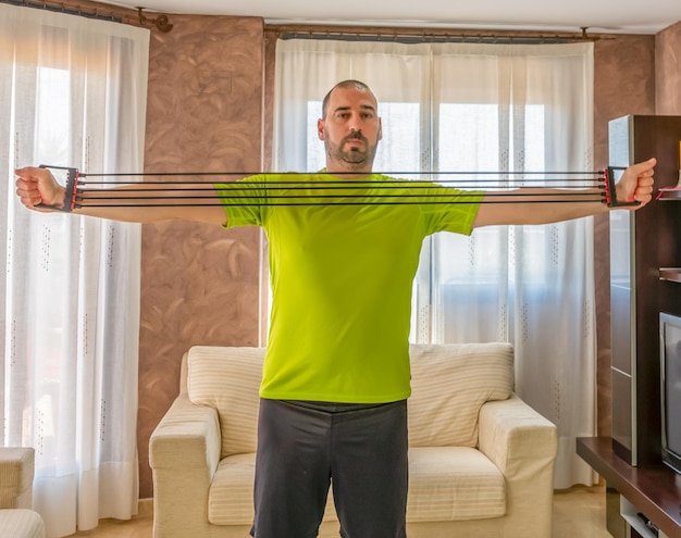 A person using resistance bands to perform a bicep curl in their home gym. The bands are stretched and provide visible resistance, highlighting their effectiveness.