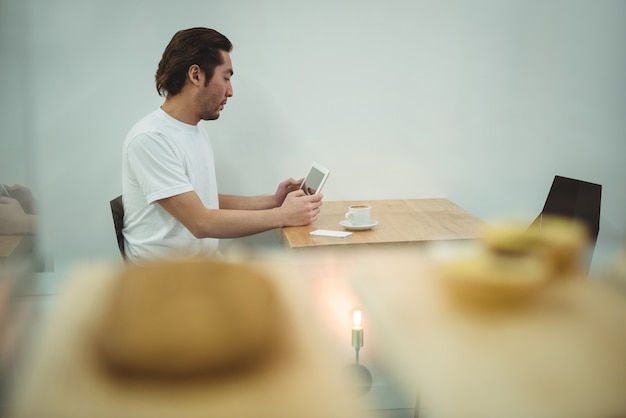 A person is placing their smartphone on a table, intentionally distancing themselves from the device. The surrounding environment is a cozy living room with soft lighting and a book on the table. The focus is on the act of disconnecting and creating a tech-free space.