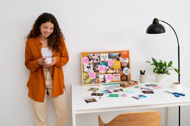 A person standing in front of their finished vision board, smiling confidently. The board is displayed in a home office and serves as a daily source of inspiration.